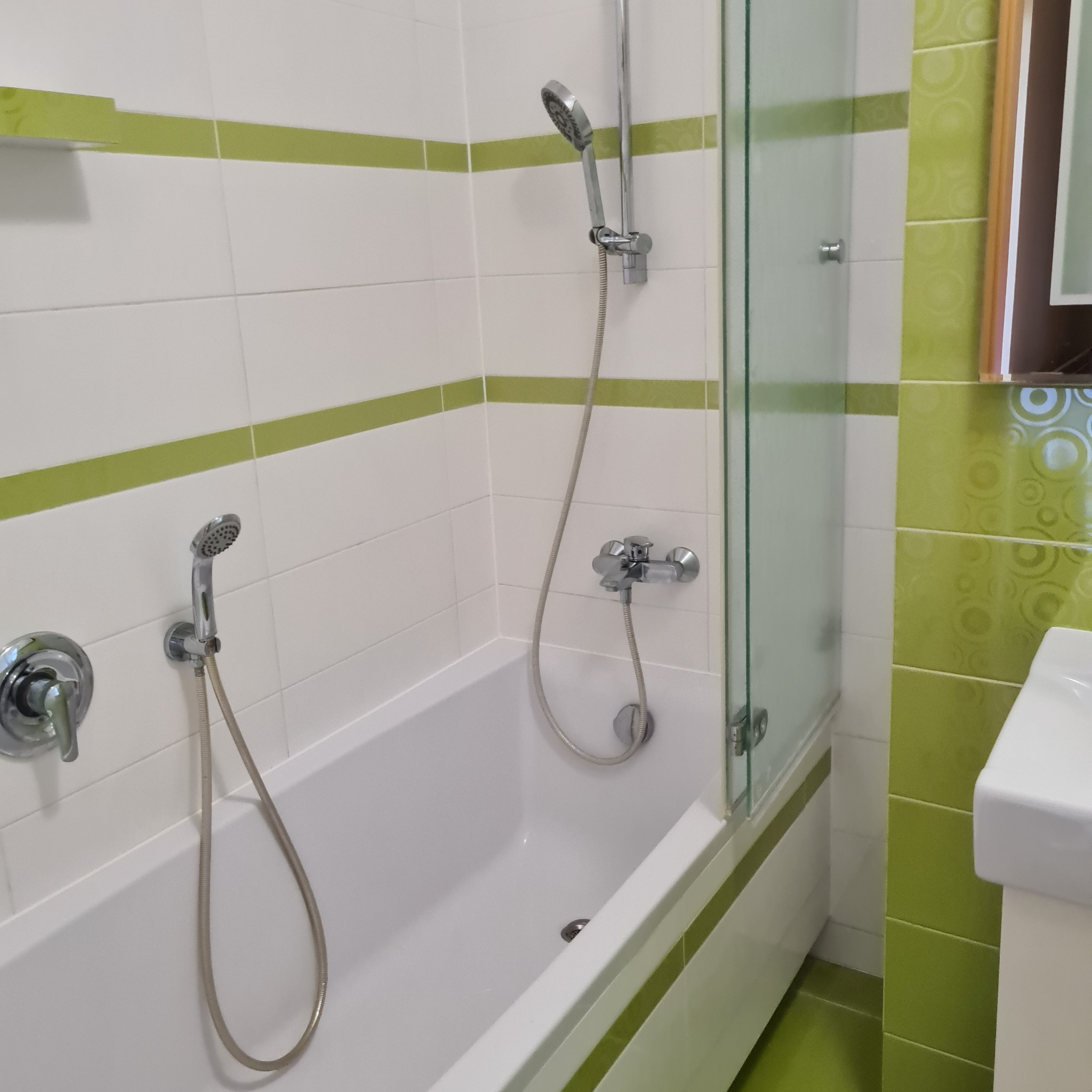 Zielono-biała łazienka z wanną i prysznicem